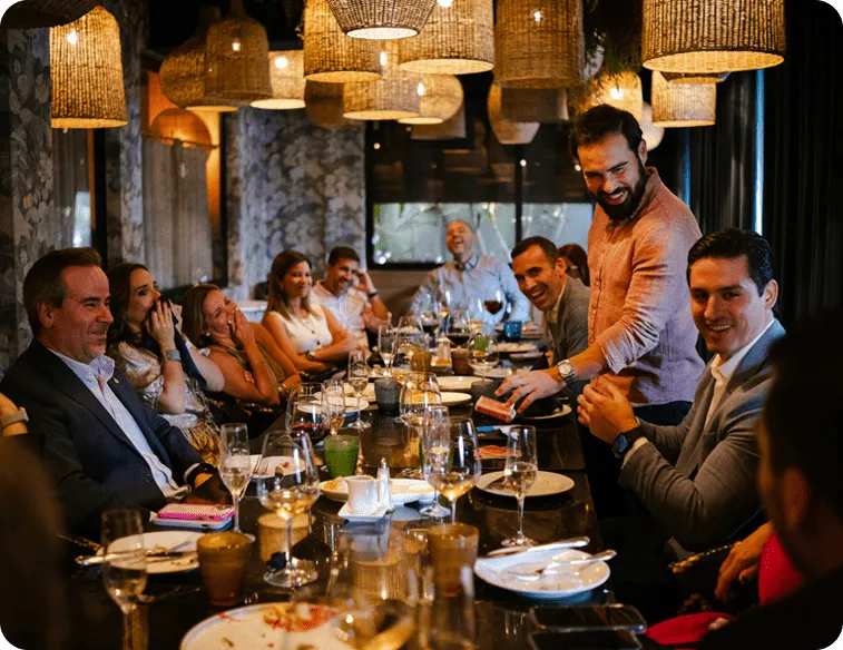 Grupo de amigos disfrutando una cena animada en restaurante.