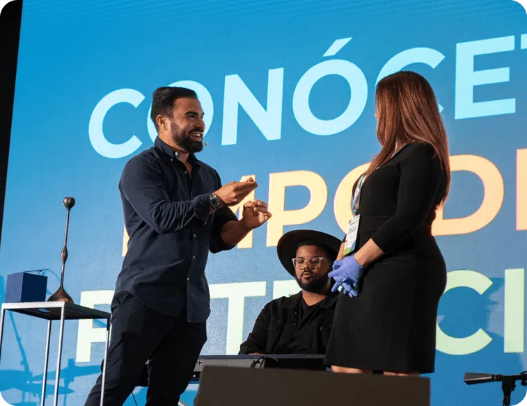 Hombre en el escenario interactuando con una mujer en evento.