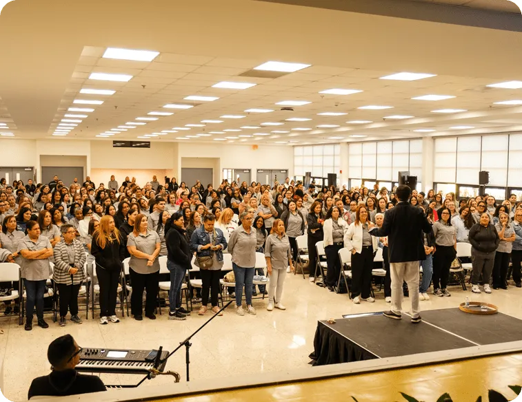Multitud en sala, un orador se dirige a la audiencia.